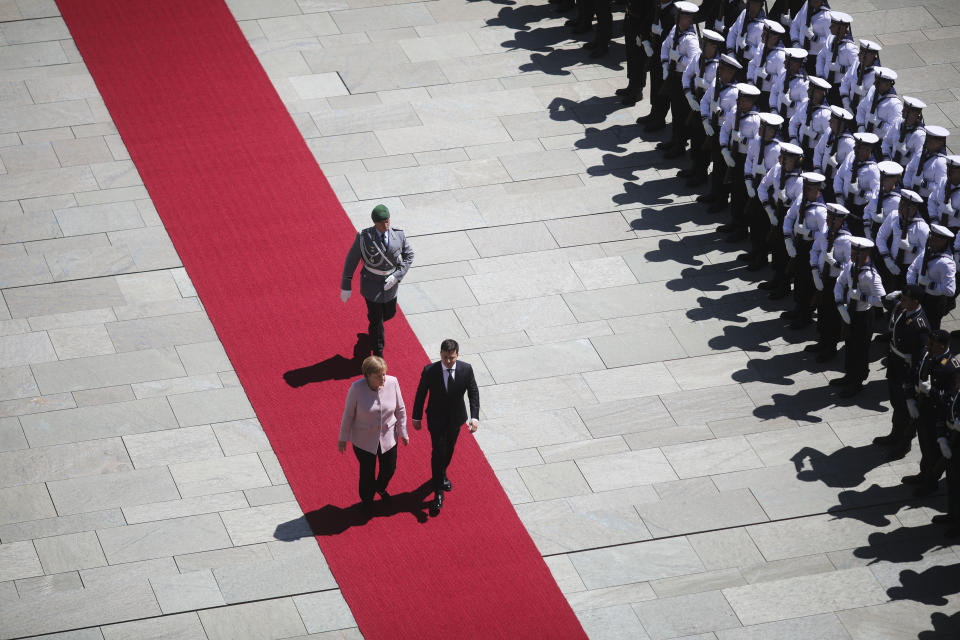 German Chancellor Angela Merkel, left, and Ukrainian President Volodymyr Zelenskiy, right, review the honour guards during the welcoming ceremony prior to a meeting at the chancellery in Berlin, Germany, Tuesday, June 18, 2019. (AP Photo/Markus Schreiber)