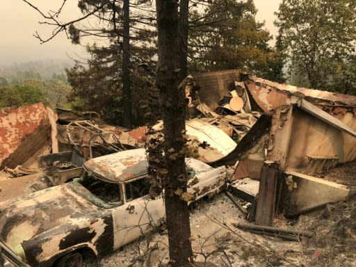 The remains of an antique car collection lie in a fire-devastated neighborhood near Redding, California