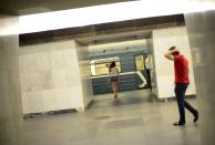 A woman and a man hold their heads as they walk toward a train at a Russian Metro station in Moscow August 11, 2013. To step onto the Moscow metro is to step back in time and immerse yourself in a museum rich in architecture and history. Opened in 1935, it is an extravagant gallery of Communist design, featuring Soviet artworks, statues, chandeliers, stained glass and ceiling mosaics. Built under Stalin, the metro now transports 7 to 9 million people a day and costs 30 Rubles, around $1, for a single ride. Picture taken August 11, 2013. REUTERS/Dylan Martinez (RUSSIA - Tags: TRANSPORT SOCIETY) ATTENTION EDITORS: PICTURE 08 OF 24 FOR PACKAGE 'RIDING THE MOSCOW METRO' SEARCH 'MOSCOW CHANDELIERS' FOR ALL IMAGES