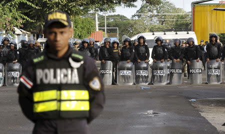 Nicaraguan riot police stand behind a Costa Rican police officer at a border post with Nicaragua in Penas Blancas, Costa Rica November 16, 2015. REUTERS/Juan Carlos Ulate