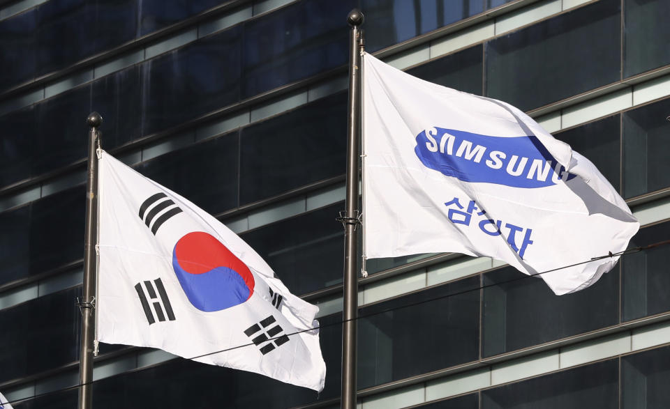 FILE - The company flag of Samsung Electronics, right, flutters next to the South Korean national flag in Seoul, South Korea, on Jan. 16, 2017. Samsung Electronics is shifting away from fossil fuels and aiming to entirely power its global operations with clean electricity by 2050, a challenging goal that experts say could be hampered by South Korea’s modest climate change commitments. Apc move photos already sent. (AP Photo/Lee Jin-man, File)