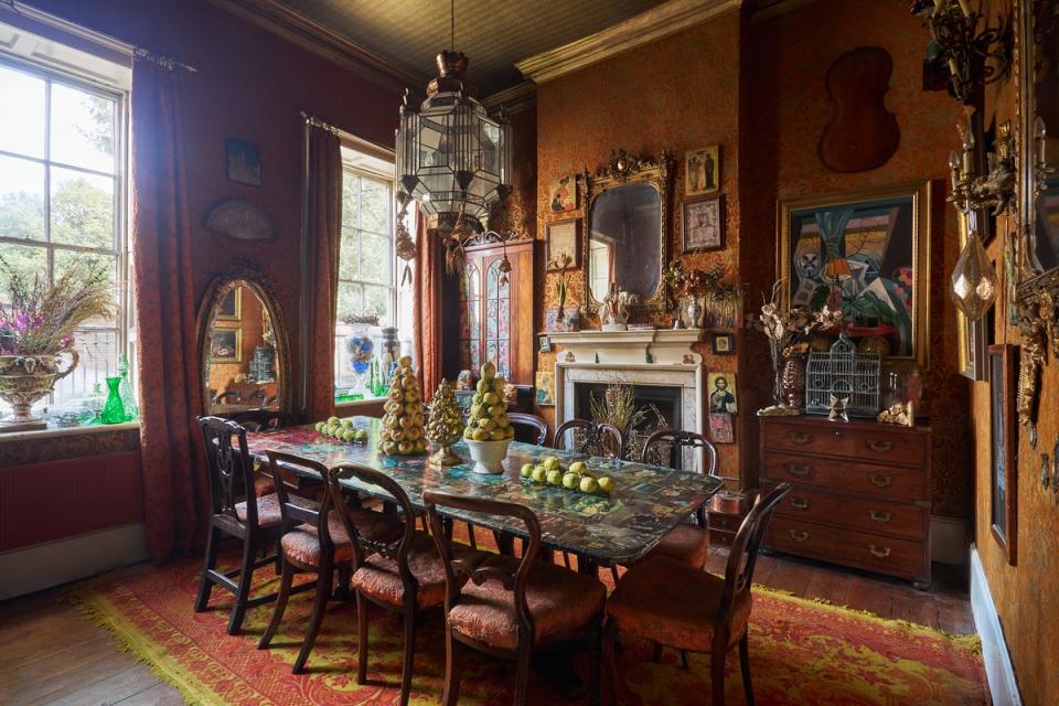 The dining room is wrapped in orange-and-gold damask wallpaper (Kinleigh Folkard & Hayward)