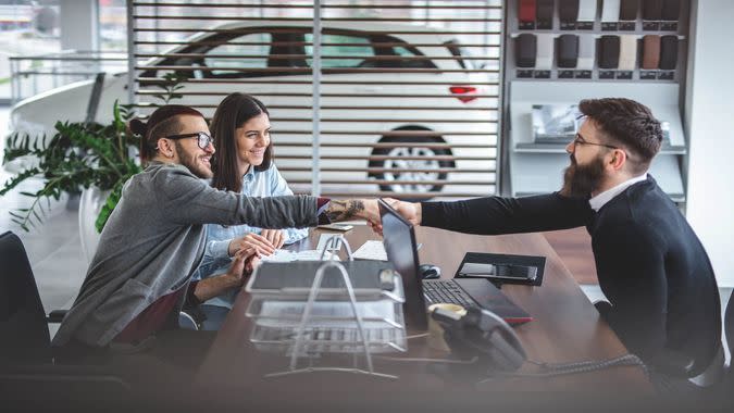 Young and handsome hipster man, buying a new car with his girlfriend, from the car saloon.