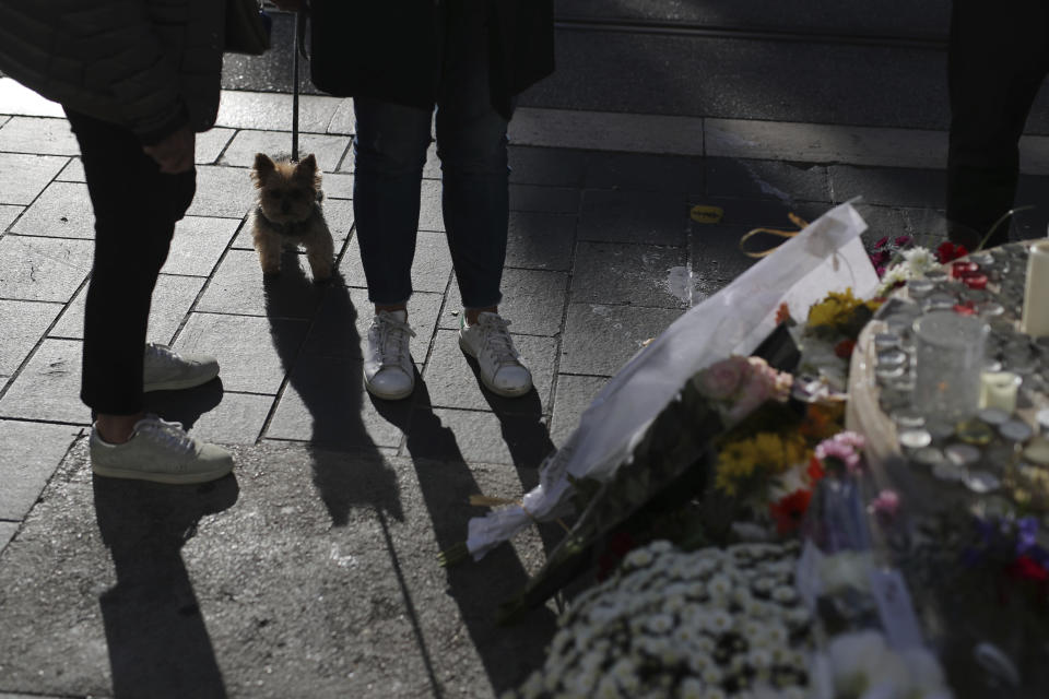 People stand near flowers, messages and candles outside Notre Dame church, in Nice, France, Friday, Oct. 30, 2020. A new suspect is in custody in the investigation into a gruesome attack by a Tunisian man who killed three people in a French church. France heightened its security alert amid religious and geopolitical tensions around cartoons mocking the Muslim prophet. (AP Photo/Daniel Cole)