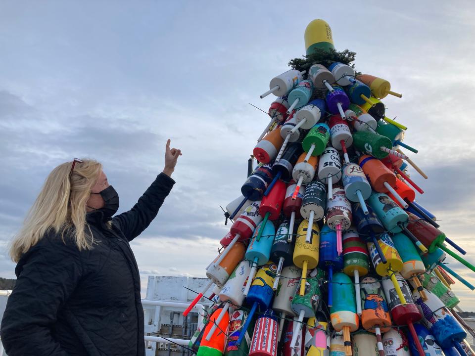 Kelly Philbrook points Tuesday, Dec. 1, 2021, to the top buoy on Kittery's first holiday lobster buoy tree, which was decorated in memory of town fishermen Dave Baxter, who died in the summer.