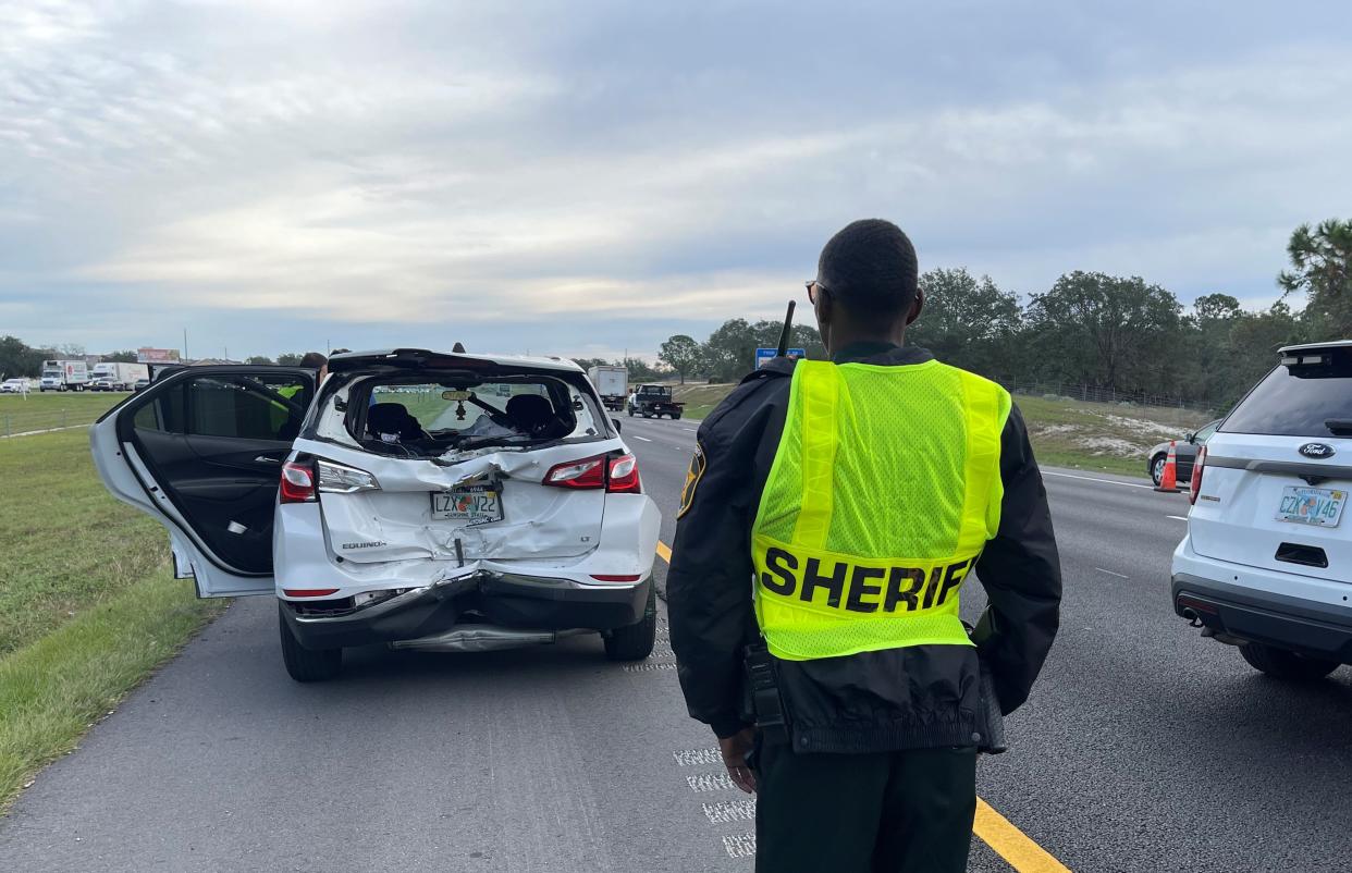 A Polk County Sheriff's Office employee stands near a vehicle along I-4 after a motorcyclist crashed into the back of it while traveling eastbound.
