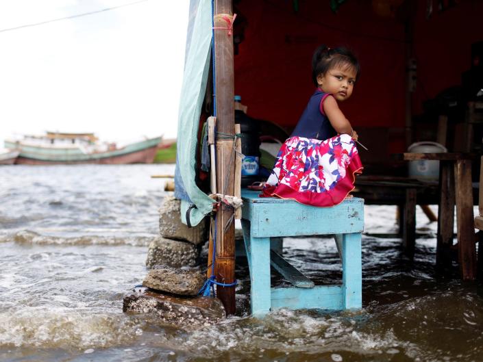 el aumento de los mares rodea a una niña en un banco