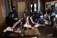 Millaray Huichalaf, a Mapuche machi, or healer and spiritual guide, cradles her 2-year-old daughter, Anukeu, as her brother prepares racks of lamb for celebrations of We Tripantu, the Mapuche new year, at her home in Carimallin, southern Chile, Saturday, on June 25, 2022. "In addition to being a healer, I'm also a militant in Mapuche resistance. Every day that I wake up, I think about how I can keep defending the river," Huichalaf says. She also hopes her daughters will continue the fight. (AP Photo/Rodrigo Abd)