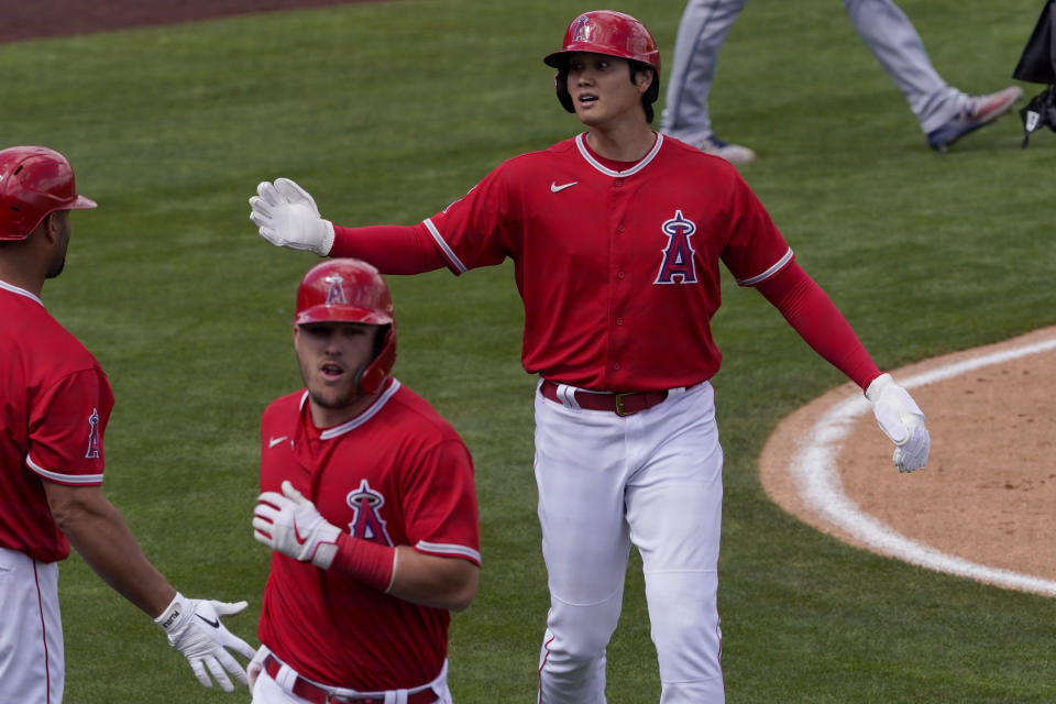 Los Angeles Angels' Shohei Ohtani right, and Mike Trout scores on a fly out hit by Justin Upton during the first inning of a spring training baseball game against the Cleveland Indians, Tuesday, March 16, 2021, in Tempe, Ariz. (AP Photo/Matt York)