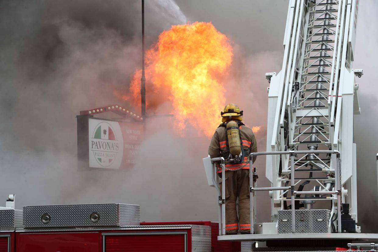 An Akron firefighter mans a water truck as firefighters more firefighters from Akron and Fairlawn work to douse a raging fire at Pavona's Pizza in October 2022. The fire completely destroyed the restaurant at West Market Street and Sand Run Road and damaged other nearby businesses.