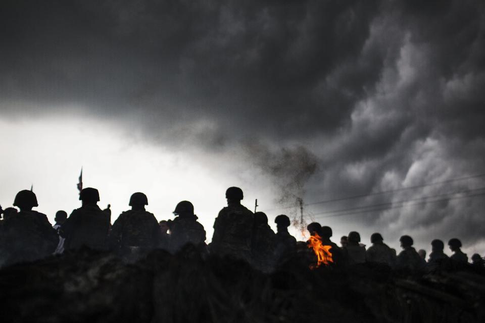 Ukrainian Army soldiers line up in front of Pro Russia civilians who where blocking the road in the Andreevka, 10 km south to Slaviansk , Ukraine, Friday, May 2, 2014. Russia has massed tens of thousands of troops in areas near Ukraine’s border. Kiev officials claim Russia is preparing to invade and that it is fomenting the unrest in the east, where insurgents have seized government buildings in about a dozen cities in towns. Moscow denies the allegations, but Foreign Minister Sergey Lavrov has warned Russia would respond to attacks on Russian citizens or interests in the east. (AP Photo/Manu Brabo)