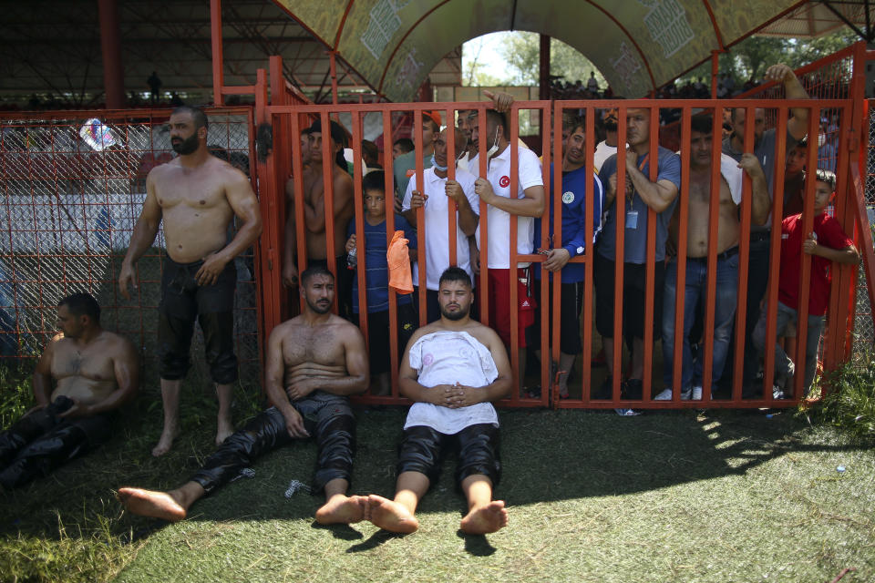 Fans watch as restlers rest after they competed on the second day of the 660th instalment of the annual Historic Kirkpinar Oil Wrestling championship, in Edirne, northwestern Turkey, Saturday, July 10, 2021.Thousands of Turkish wrestling fans flocked to the country's Greek border province to watch the championship of the sport that dates to the 14th century, after last year's contest was cancelled due to the coronavirus pandemic. The festival, one of the world's oldest wrestling events, was listed as an intangible cultural heritage event by UNESCO in 2010. (AP Photo/Emrah Gurel)