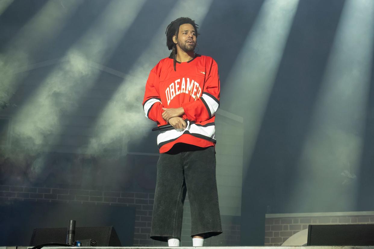 J. Cole standing onstage