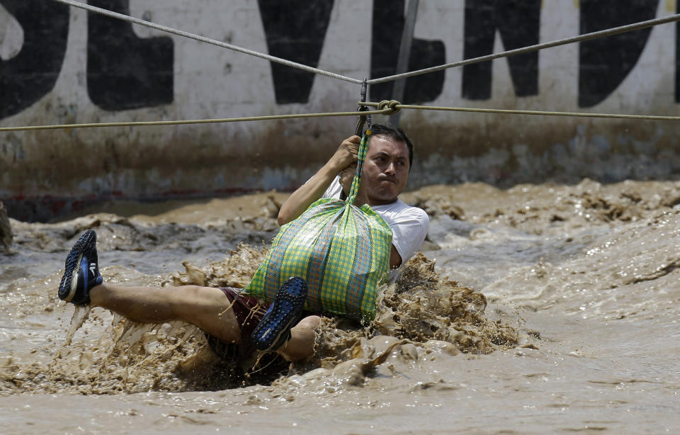 A man is pulled to safety on a zipline harness in Lima, Peru, Friday, March 17, 2017. The number of people killed in Peru following intense rains and mudslides wreaking havoc around the Andean nation climbed to 67 Friday, with thousands more displaced from destroyed homes and others waiting on rooftops for rescue. (AP Photo/Martin Mejia)