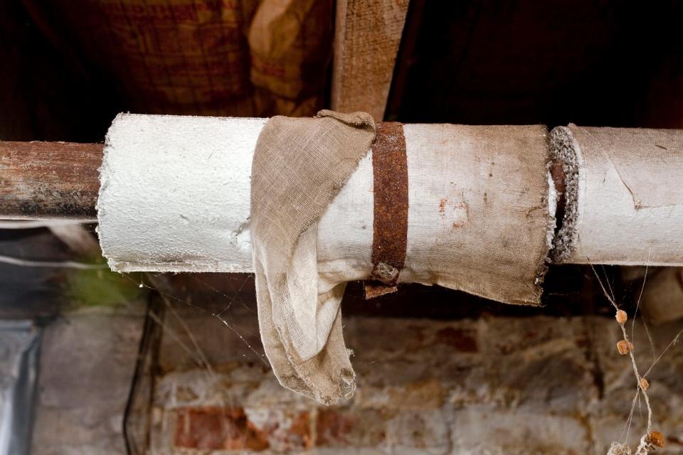 Basement plumbing pipes wrapped with asbestos insulation.