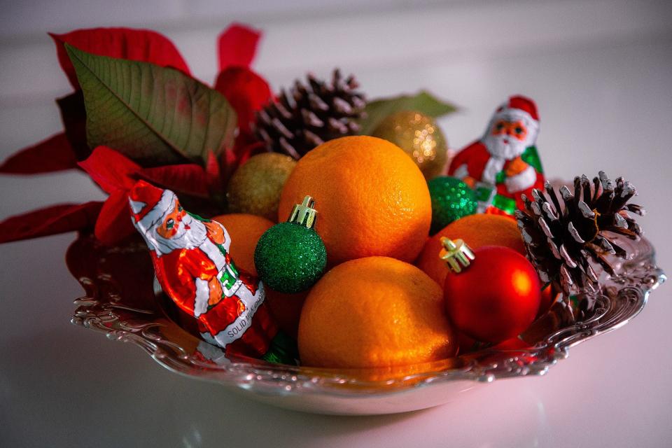 An inexpensive holiday arrangement of citrus, pinecones, chocolates and ornaments punctuate the table at Penny Murphy's home.