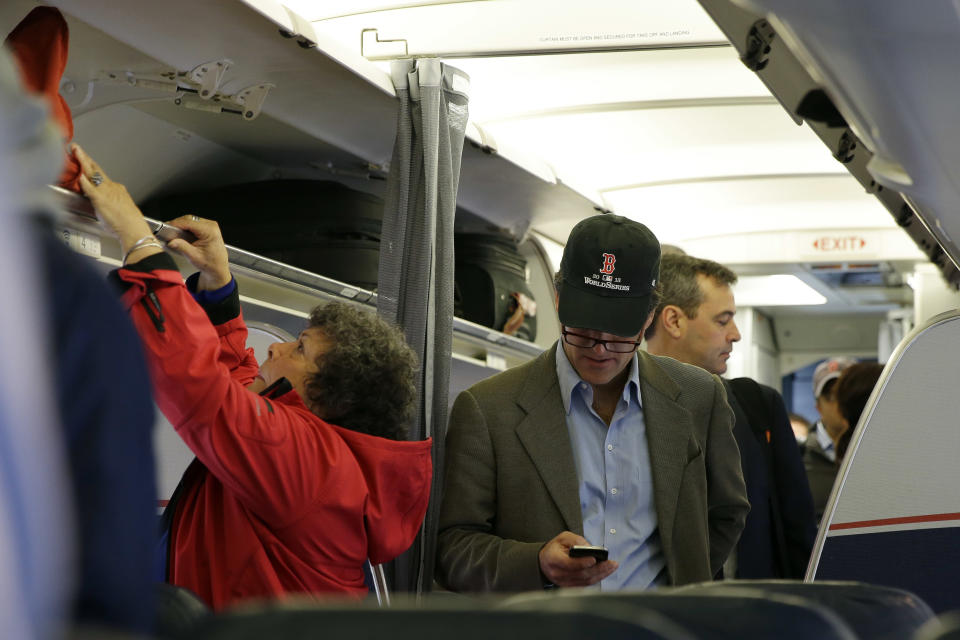 FILE - In this Thursday, Oct. 31, 201 file photo, a passenger checks his cell phone while boarding a flight, in Boston. For the past decade fliers haven't been able to use electronic devices while planes are below 10,000 feet because they might interfere with cockpit instrument, but the Federal Aviation Administration declared Thursday Nov. 21, 2013, that interference isn't a concern anymore. (AP Photo/Matt Slocum, File)