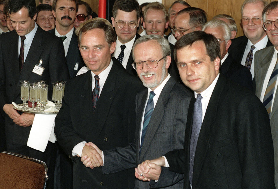 FILE - West German Secretary of State Wolfgang Schaeuble, left, his East German counterpart Guenther Krause, right, and East German Prime Minister Lothar de Maizire, center, symbolically holding hands following the signing of the German unification treaty in East Berlin, Friday, Aug. 3, 1990. Wolfgang Schaeuble, who helped negotiate German reunification in 1990 and as finance minister was a central figure in the austerity-heavy effort to drag Europe out of its debt crisis more than two decades later, has died on Tuesday, Dec. 26, 2023. He was 81. (AP Photo/Hansjoerg Krauss, File)