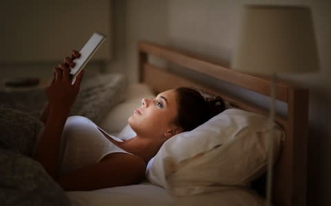 Woman using her tablet in bed - Credit: PeopleImages/Digital Vision