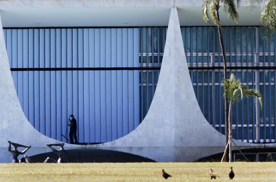 A worker cleans outside the presidential residence, Alvorada Palace, in Brasilia, Brazil, Tuesday, July 7, 2020. Bolsonaro said Tuesday he has tested positive for COVID-19. (AP Photo/Eraldo Peres)