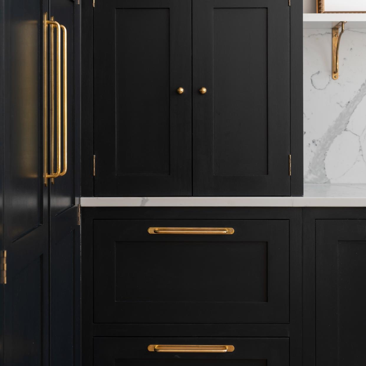  A dark kitchen with brass hardware handles 