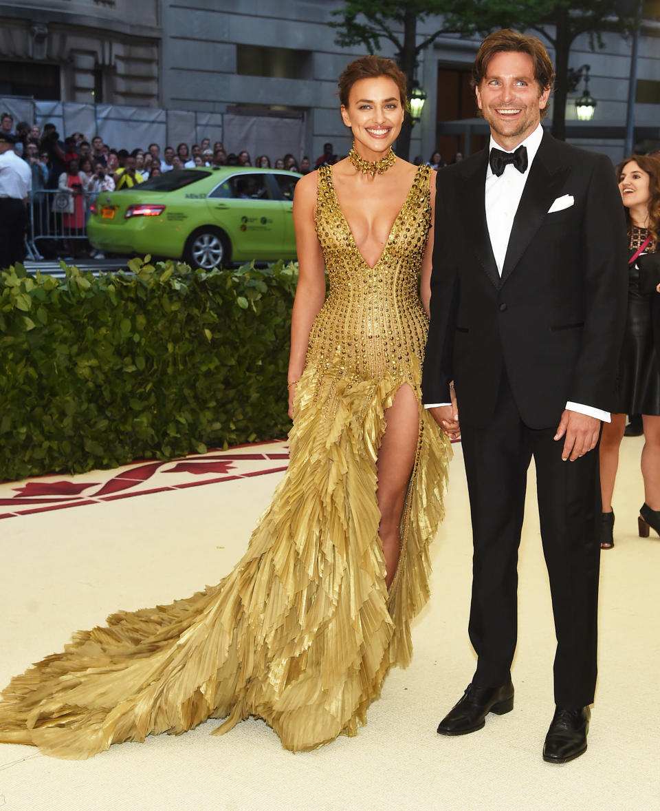 <p>Irina Shayk shimmered in this feathered Versace gold dress alongside her beau, Bradley Cooper. Photo: Getty Images </p>