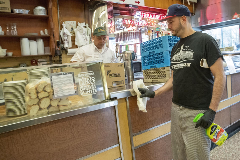 In this March 19, 2020 photo, an employee disinfects the counter at Katz's Delicatessen on the Lower East Side of New York. The iconic eatery is only open for take out and delivery orders due to the coronavirus outbreak. (AP Photo/Mary Altaffer)