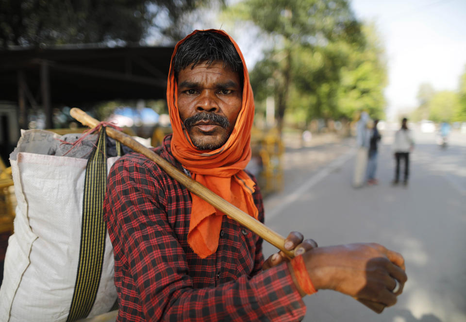 Hiralal, a daily wage laborer, leaves for his village as the city comes under lockdown in Prayagraj, India , Thursday, March 26, 2020. Some of India's legions of poor and people suddenly thrown out of work by a nationwide stay-at-home order began receiving aid distribution Thursday, as both the public and private sector work to blunt the impact of efforts to curb the coronavirus pandemic. Untold numbers of them are now out of work and many families have been left struggling to eat. (AP Photo/Rajesh Kumar Singh)