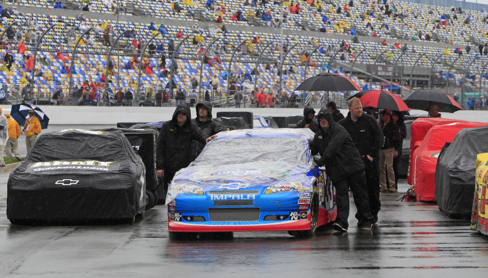 Crew members push driver Elliott Sadler's car down the starting grid in the rain before the NASCAR Daytona 500 Sprint Cup series auto race at Daytona International Speedway in Daytona Beach, Fla., Sunday, Feb. 26, 2012. (AP Photo/John Raoux)