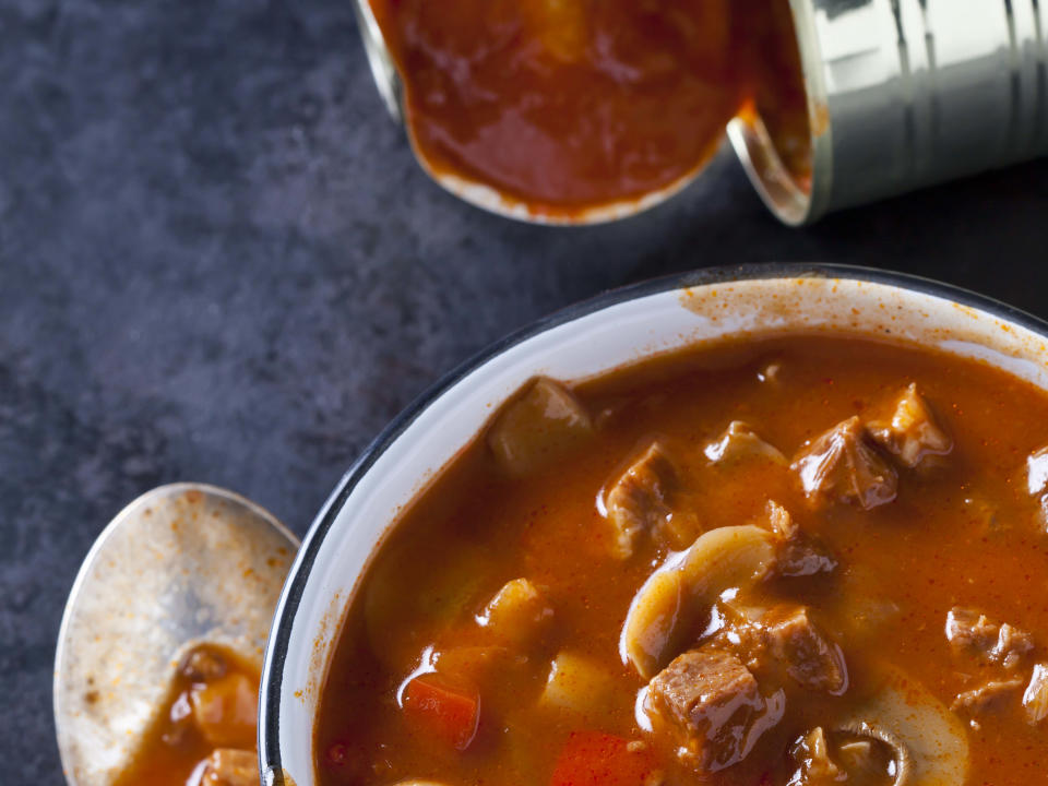 Canned soup in a bowl, next to an open can and a spoon. (Photo via Getty Images)