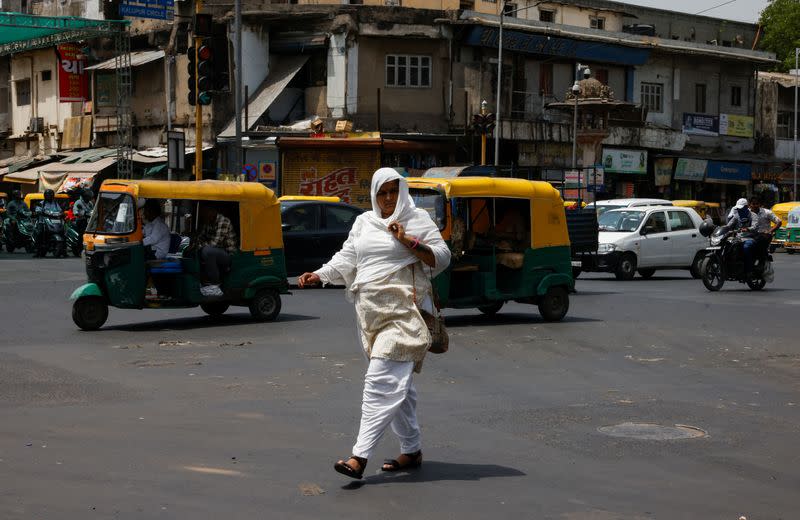 A woman covered with a cloth to protect herself from the heat walks on a road during a heatwave in Ahmedabad