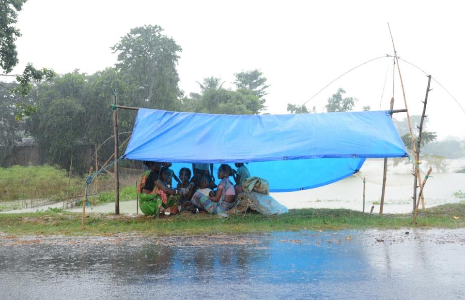 Flood affected villagers sit under a temporary shelter during rainfall in a flood affected area in Morigaon district of Assam (EPA)
