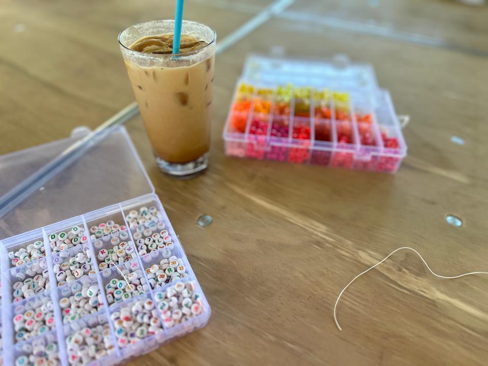 Iced latte and two trays of colorful beads sitting on a wooden table