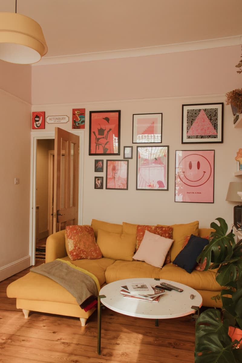 A yellow fabric couch below a gallery wall.