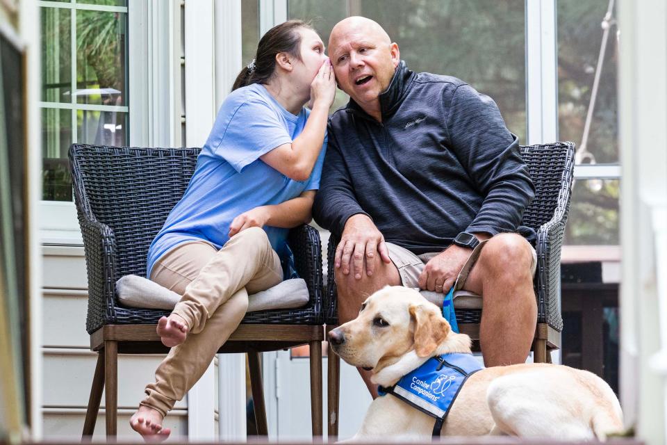 Jazmin Tinsley whispers a response to an interview question in her dad Kevin's ear, while her new service dog, Bonus, looks at the camera on the back porch of the Tinsley family home in Rehoboth Beach, Wednesday, Sept. 27, 2023. Jazmin dreams of being a teacher and living independently one day.