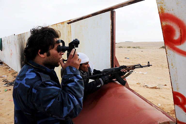 Libyan rebel fighters scan the horizon for approaching tanks of Kadhafi loyalist forces as they take position at a gate of the north-central key Libyan oil town of Ras Lanuf