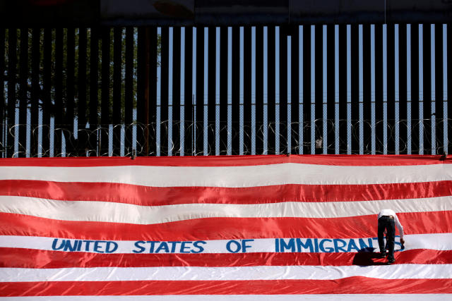 Roberto Marquez, known as Roberz, writes on a large U.S. flag as part of a protest called &#39;United States of Immigrants&#39;, aimed to demand respect for the migrants, near a border wall in El Paso, Texas, as pictured from Ciudad Juarez, Mexico June 6, 2019. REUTERS/Jose Luis Gonzalez     TPX IMAGES OF THE DAY