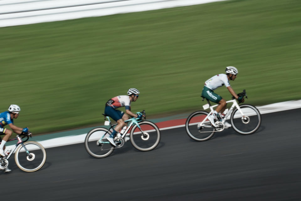 Simon Philip Yates of Great Britain, center, is seen in this slow shutter speed photo, comptes during the men's cycling road race at the 2020 Summer Olympics, Saturday, July 24, 2021, in Oyama, Japan. (AP Photo/Thibault Camus)