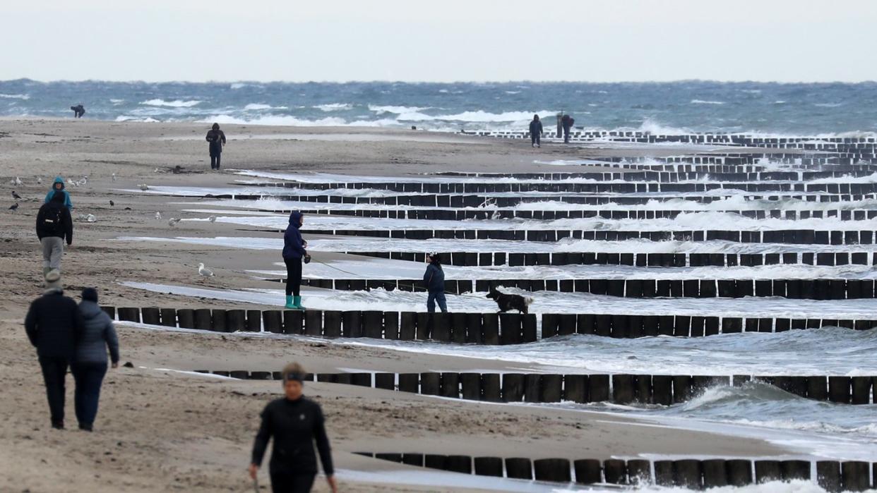 Spaziergänger sind am Strand bei Graal-Müritz unterwegs.