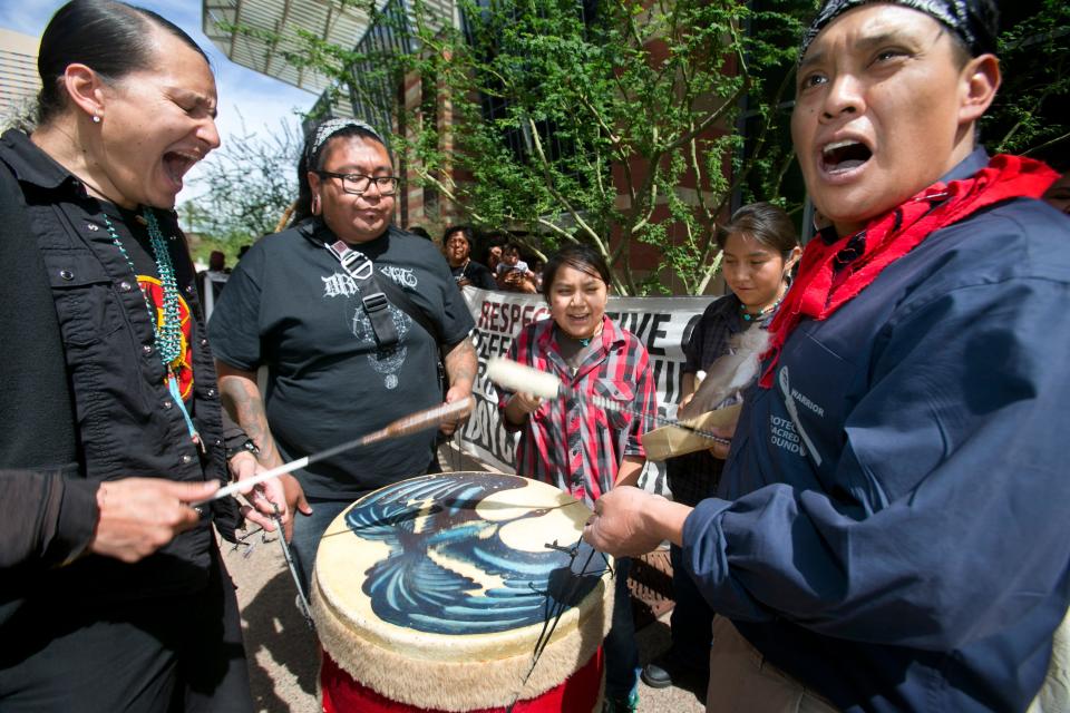 Klee Benally, left, of Flagstaff, who is Navajo, bangs a drum during rally defending the development of lands sacred to Native American people outside the Phoenix Convention Center on Tuesday, March 26, 2013.