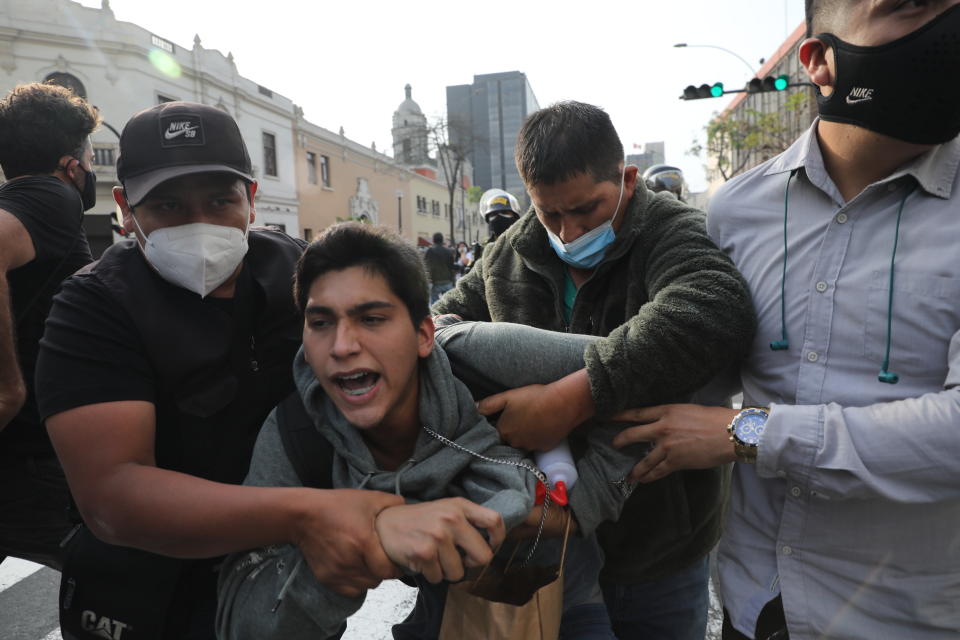 Plainclothes policemen detain a supporter of ousted President Martin Vizcarra near a police barricade, preventing marchers who are refusing to recognize the new government from reaching Congress, in Lima, Peru, Wednesday, Nov. 11, 2020. On Tuesday, Peru swore in Manuel Merino as president, after Peru’s legislature booted Vizcarra from office on Monday. (AP Photo/Rodrigo Abd)