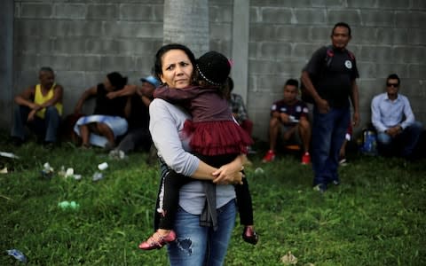 A Honduran woman carries her daughter as they wait to leave with a new caravan of migrants in San Pedro Sula - Credit: &nbsp;JORGE CABRERA/&nbsp;REUTERS