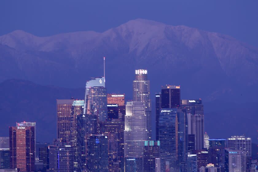 LOS ANGELES, CALIF. - FEB. 23, 2022. Snow covers Mt. Baldy behind the Los Angeles skyline on Wednesday, Feb. 23, 2022. Cold weather is expected to give way to a warming trend next week. (Luis Sinco / Los Angeles Times)