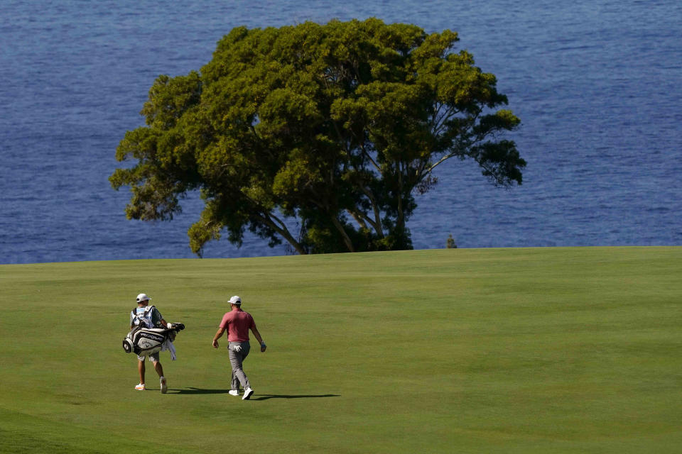 Jon Rahm, of Spain, walks along the 12th fairway with his caddy during the final round of the Tournament of Champions golf event, Sunday, Jan. 9, 2022, at Kapalua Plantation Course in Kapalua, Hawaii. (AP Photo/Matt York)