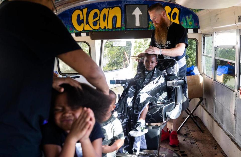 Jordan Allsup with CleanUP gives a haircut to Jaiden Rhodes, 7, as others wait for their turn on a bus converted to a barbershop and laundromat Tuesday, Aug. 9, 2022, in Fort Worth. CleanUP hosts events throughout the area to offer free haircuts and clothing.