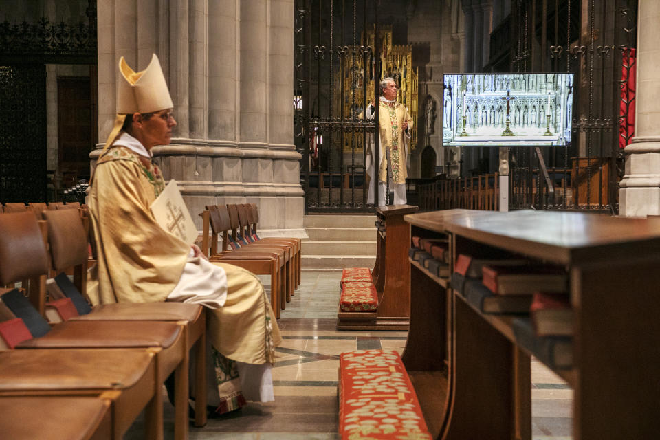 Rt. Rev. Mariann Edgar Budde, at left, Bishop of the Episcopal Diocese of Washington, and Very Rev. Randolph Marshall Hollerith, Dean of Washington National Cathedral, right, await their signal to begin a livestreamed Easter Sunday service at the National Cathedral with no parishioners, Sunday, April 12, 2020, in Washington, in light of coronavirus pandemic precautions. The large Cathedral would normally be full on Easter Sunday. (AP Photo/Jacquelyn Martin)