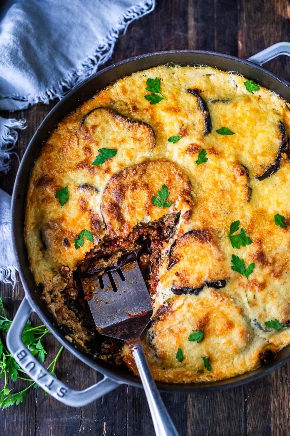 moussaka being served out of a large cast iron pan