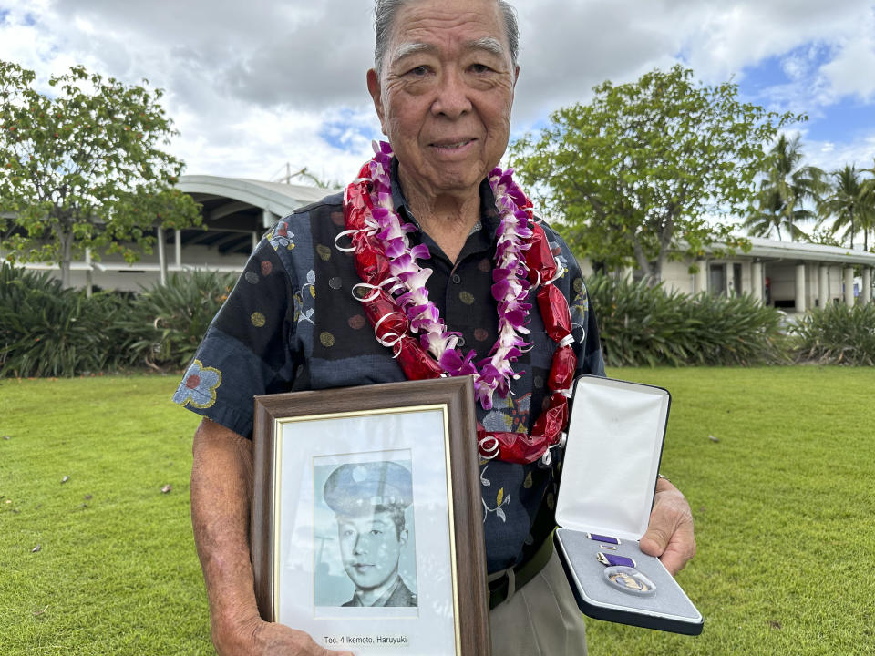 Wilfred Ikemoto holds a photo of his older brother, Haruyuki Ikemoto, and the Purple Heart medal posthumously awarded to him, in Pearl Harbor, Hawaii, on Friday, May 10, 2024. The families of five Hawaii men who served in a unit of Japanese-language linguists during World War II received posthumous Purple Heart medals on behalf of their loved ones on Friday, nearly eight decades after the soldiers died in a plane crash in the final days of the conflict. (AP Photo/Audrey McAvoy)