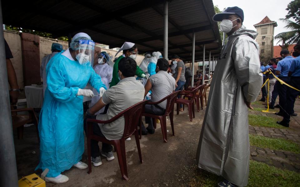 Sri Lankan health workers administer the Sinopharm vaccine in Colombo - AP