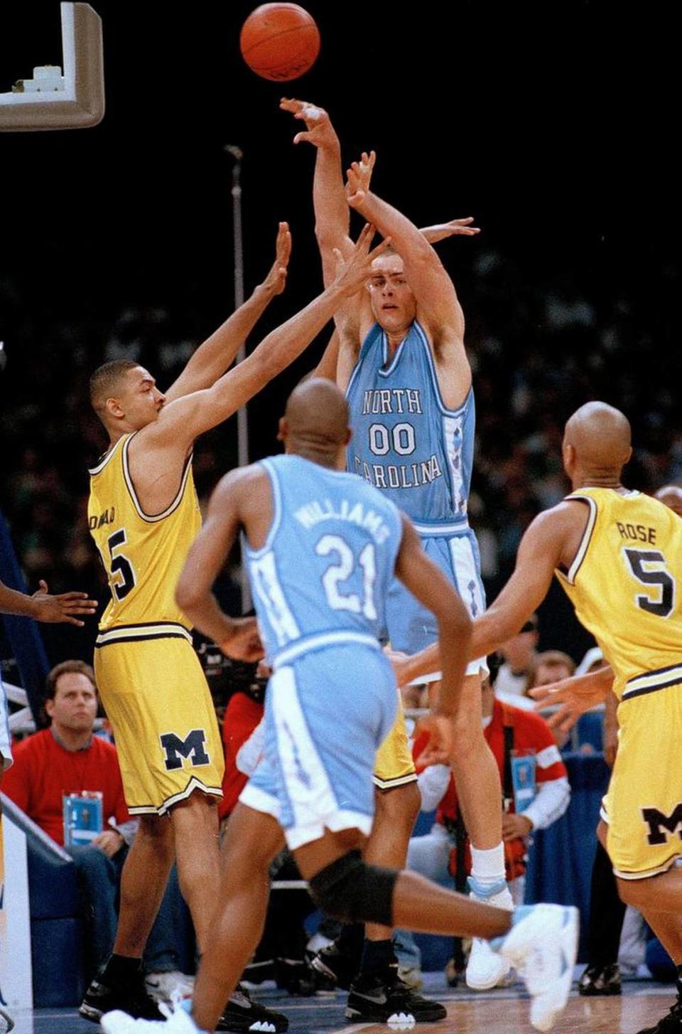 North Carolina’s Eric Montross (00) flips a pass over to teammate Donald Williams (21) as Michigan’s Juwan Howard covers during the first half of their NCAA championship game in New Orleans on April 5, 1993.